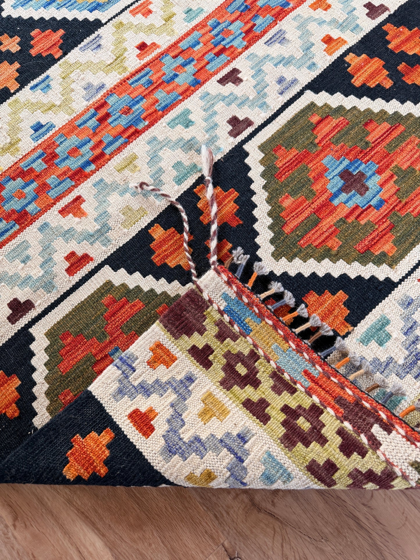 Close-up of a colorful patterned rug with geometric designs on a wooden floor.